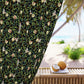 Decorative curtain with nature-themed pattern next to a table with coconuts and a beach view.