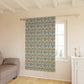Floral patterned curtain hanging in a room with a sofa and window.