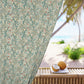 Decorative curtain with floral pattern in front of a beach view with coconuts on a table.