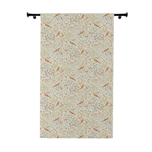 Floral and bird patterned fabric hanging on a rod against a white background