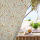 Decorative curtain with bird and floral pattern in front of a beach view.
