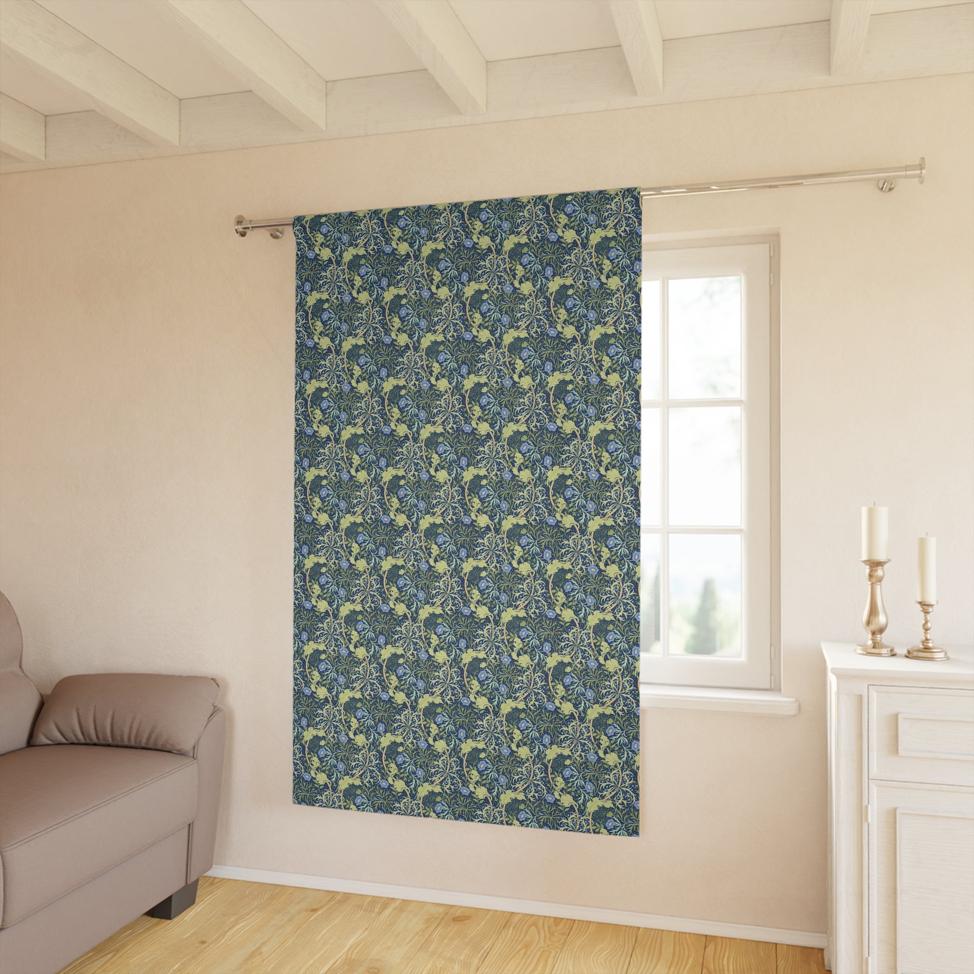 Patterned blue curtain hanging in a room with a sofa and window.
