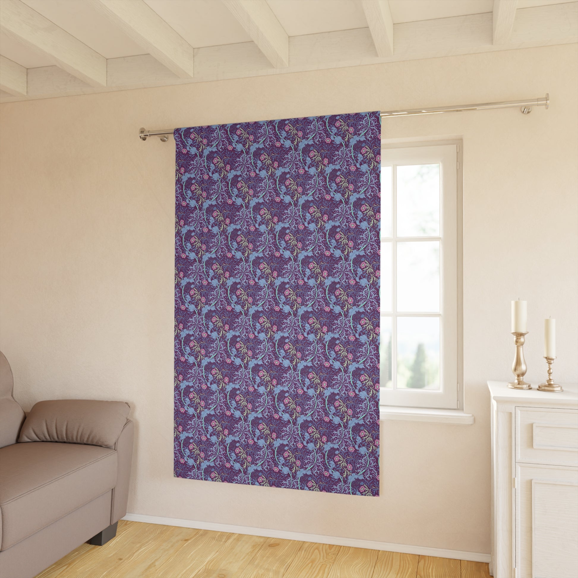 Purple floral patterned curtain hanging in a room with a sofa and window.
