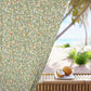 Decorative curtain with floral pattern in front of a beach view