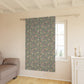 Floral patterned curtain hanging in a room with a sofa and window.