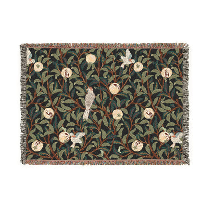 A woven cotton blanket with a geometric William Morris & Co pattern featuring birds and pomegranates in a onyx black colour, with fringed edges.