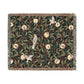 A woven cotton blanket with a geometric pattern featuring birds and pomegranates in a onyx black color, with fringed edges.