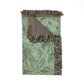 Decorative throw blanket with intricate pattern and fringed edges on a white background