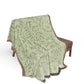 Green patterned throw blanket draped over a chair on a white background