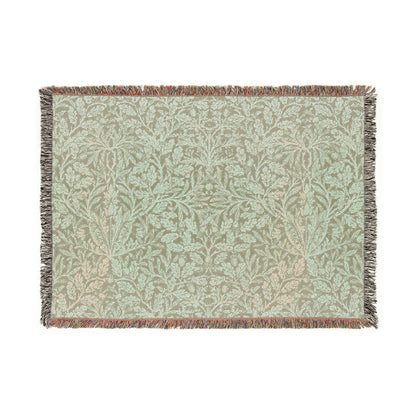 A green woven blanket with a floral pattern and colorful fringed edges displayed on a plain background.