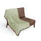 Gray blanket with turtle pattern draped over a brown chair on a white background