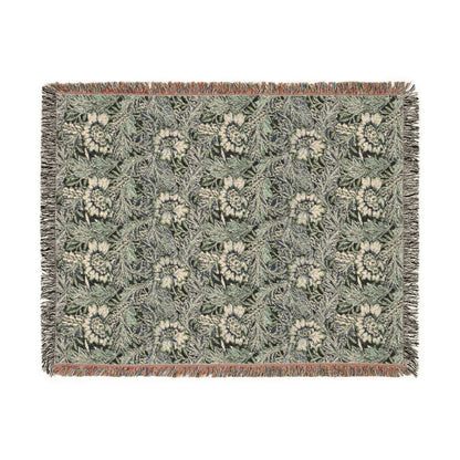 A rectangular woven throw blanket featuring a repeating floral and leaf pattern in muted green, beige, and gray tones, finished with fringed edges and a narrow rust-colored border.