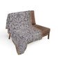 Patterned throw blanket draped over a brown chair on a white background