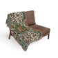 Floral-patterned blanket draped over a brown chair on a white background