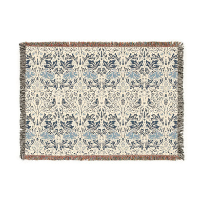 A woven cotton blanket with a geometric William Morris & Co pattern in gray, blue, and beige colours, featuring fringed edges.
