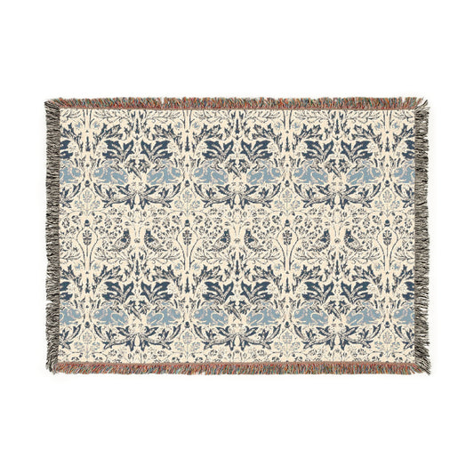 A woven cotton blanket with a geometric William Morris & Co pattern in gray, blue, and beige colours, featuring fringed edges.