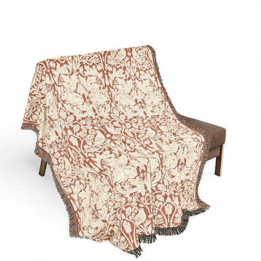 Decorative throw blanket with a floral pattern draped over a chair on a white background