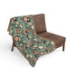 Floral patterned throw blanket draped over a brown chair on a white background