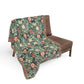 Floral patterned throw blanket draped over a brown chair on a white background