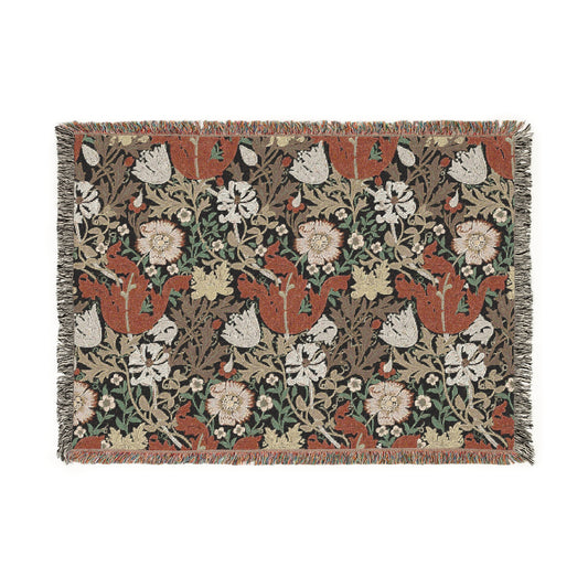 A woven cotton blanket with a geometric and floral pattern in red, green, and beige colors, with fringed edges.