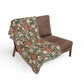 Floral-patterned blanket draped over a brown sofa on a white background