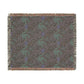 Patterned throw blanket with green and blue design on a brown background