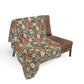Floral patterned throw blanket draped over a brown chair on a white background