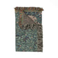 Woven blanket with leaf pattern and fringed edges on a white background