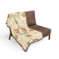 Brown chair with a floral-patterned throw blanket on a white background