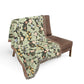 Floral patterned blanket draped over a brown chair on a white background