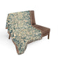 Decorative throw blanket with intricate pattern draped over a brown chair on a white background