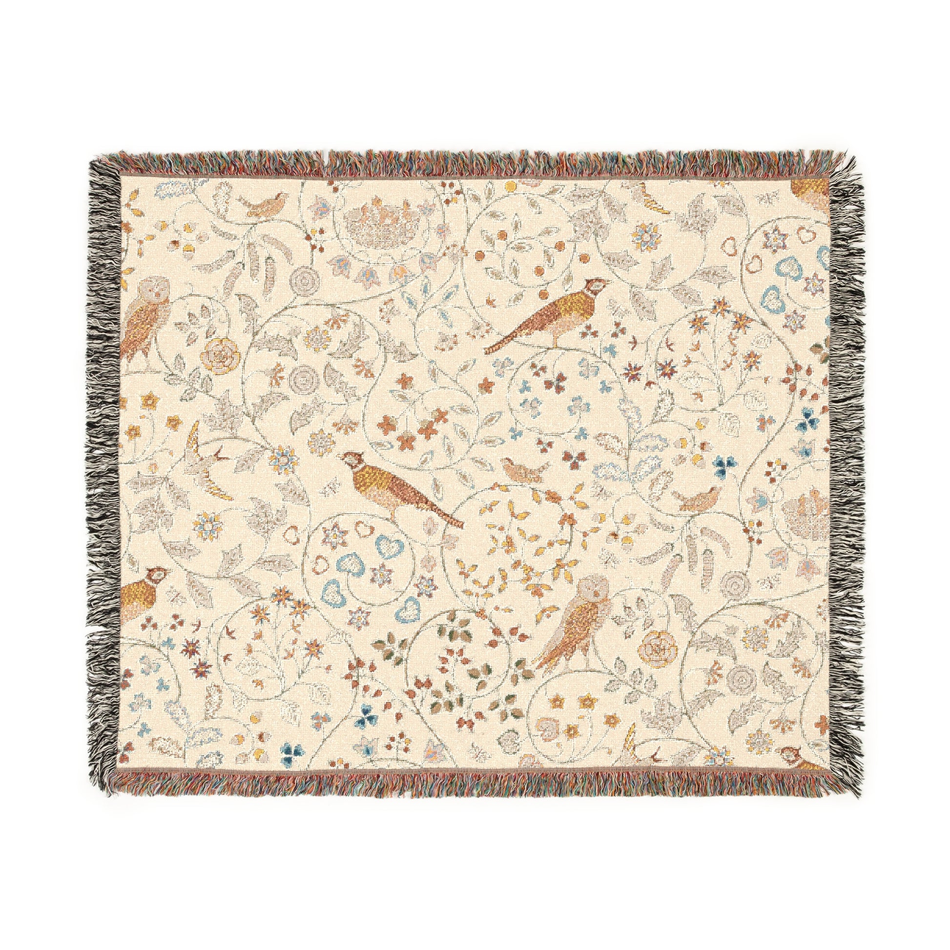A beige woven cotton blanket with a floral and bird pattern, featuring a colorful fringed edge.