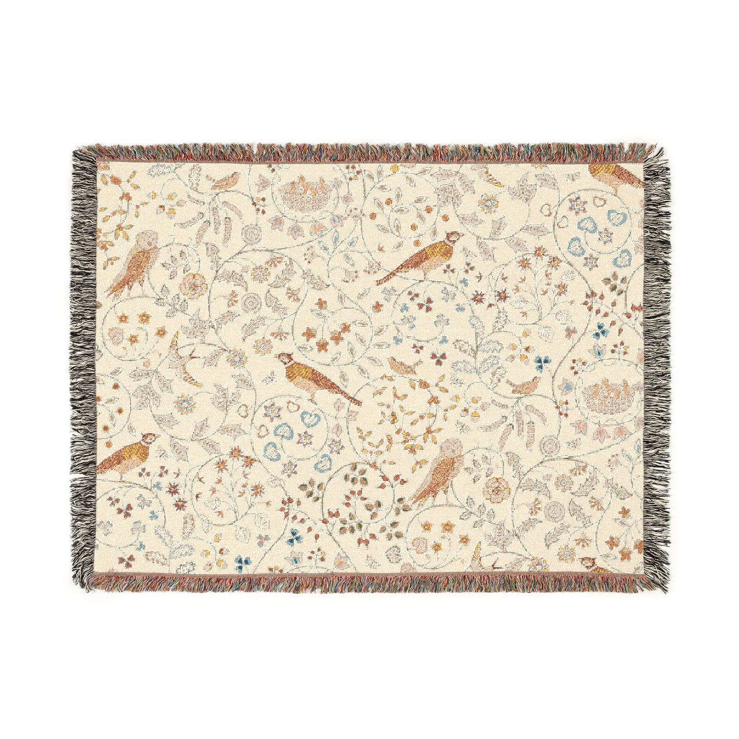 A beige woven cotton blanket with a floral and bird pattern, featuring a colorful fringed edge.