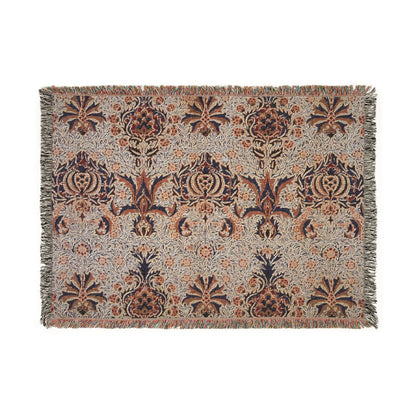 A woven cotton blanket with a geometric William Morris & Co pattern in shades of brown, beige, and black, with a colourful fringed edge.