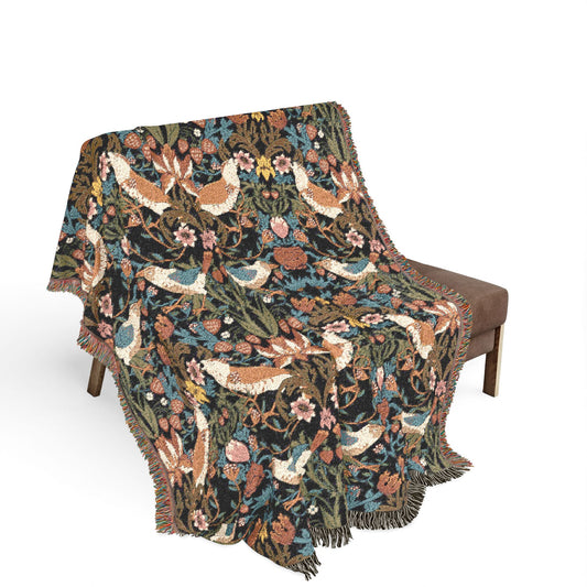 Decorative blanket with bird and floral pattern draped over a chair on a white background