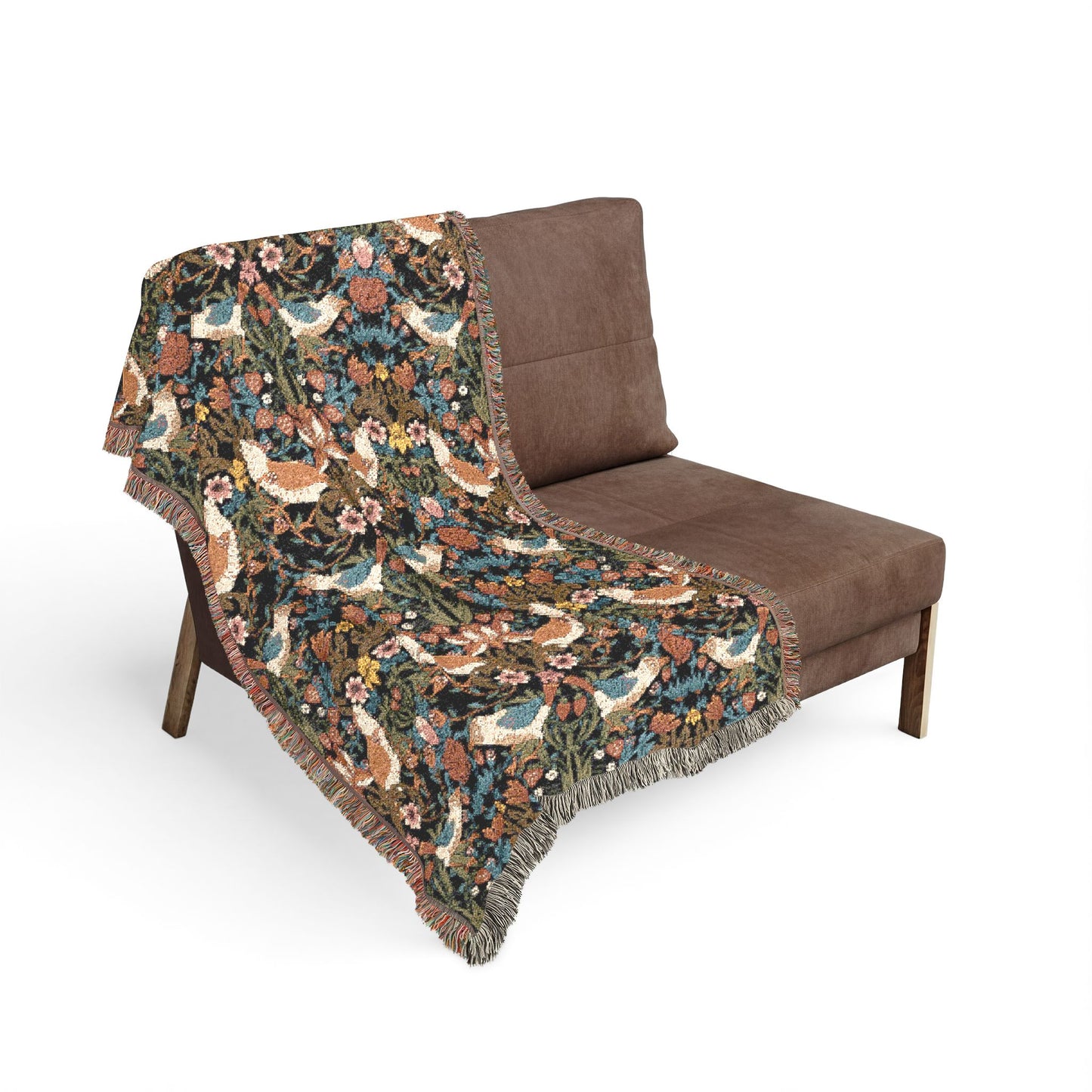 Floral and bird patterned throw blanket draped over a brown chair on a white background