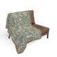 Floral patterned throw blanket draped over a brown chair on a white background