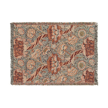 A woven cotton blanket with a geometric and floral William Morris & Co pattern in red, blue, beige, and brown colours, with fringed edges.