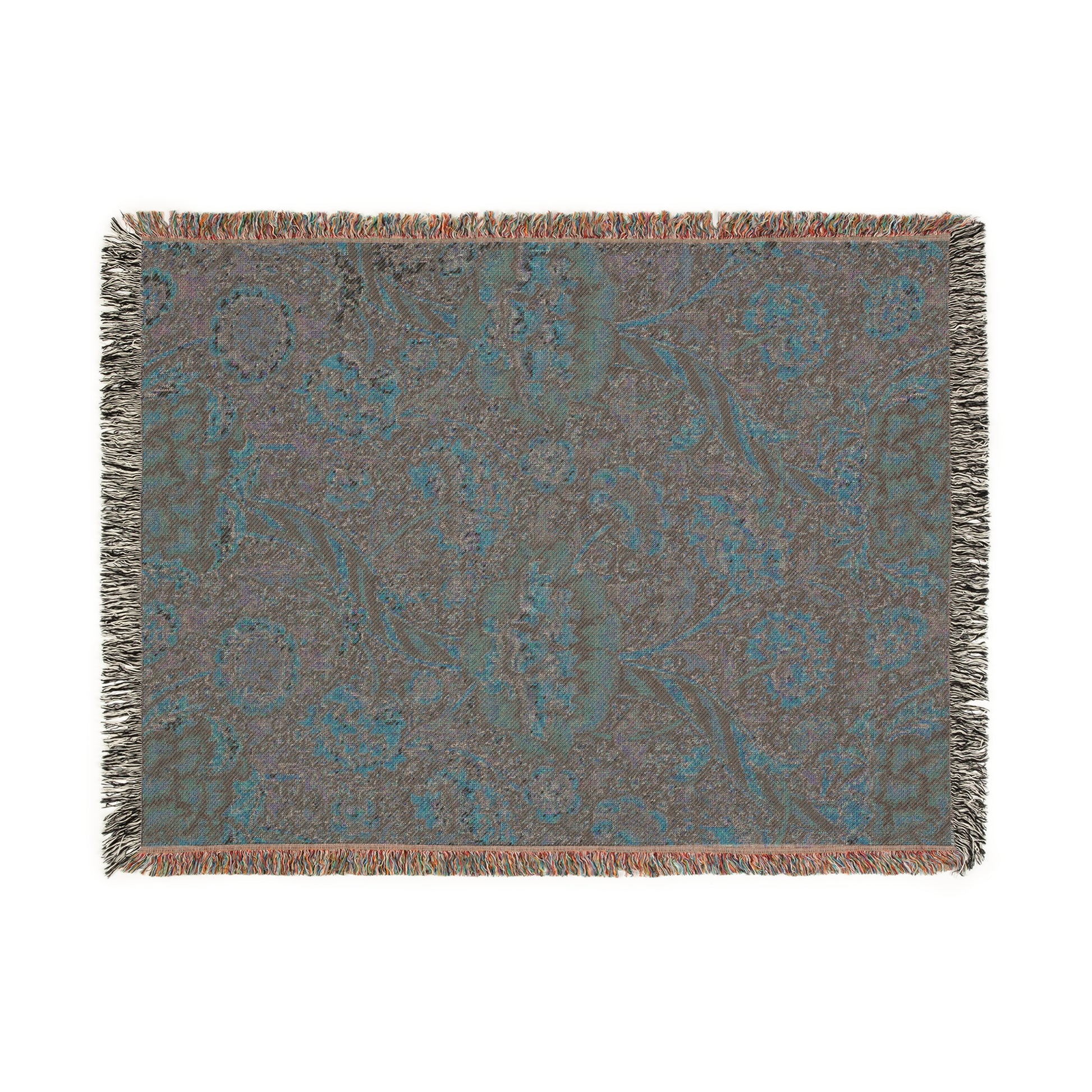 A woven cotton blanket with a geometric and floral William Morris & Co pattern in red, blue, beige, and brown colours, with fringed edges.