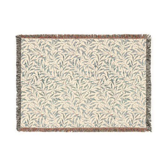 A rectangular woven cotton blanket with a William Morris & Co floral pattern in subtle colours, featuring a colourful fringed edge.