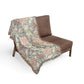 Floral patterned throw blanket draped over a brown chair on a white background