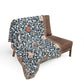 Floral patterned throw blanket draped over a brown chair on a white background