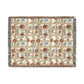 A woven cotton blanket with a geometric pattern featuring floral motifs and a colorful edge fringe.