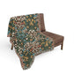 Floral patterned blanket draped over a brown chair on a white background