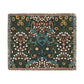 A woven cotton blanket with a floral pattern in multiple colors, including green, blue, and red, with fringed edges.
