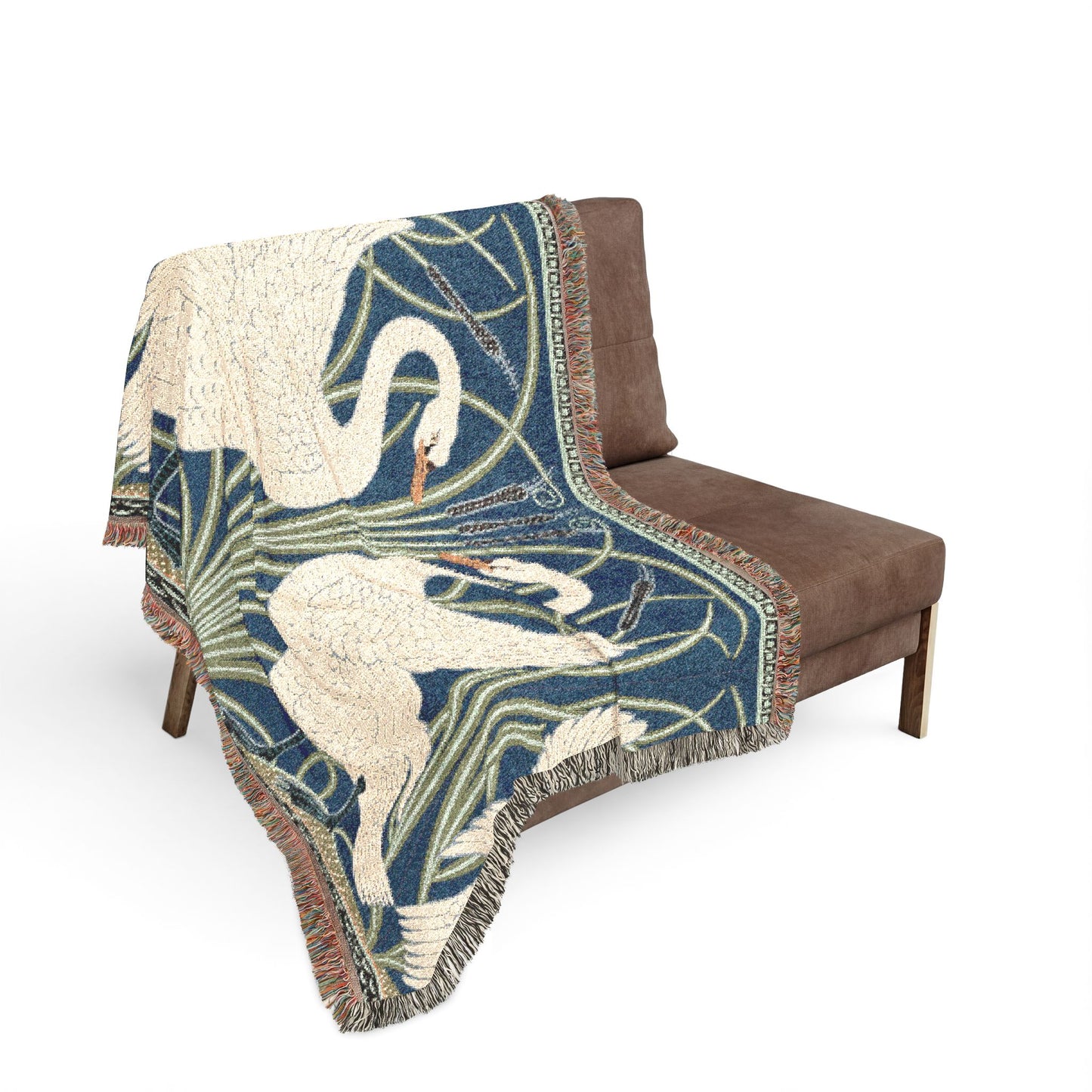 Decorative throw blanket with swan design draped over a brown chair on a white background
