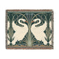 A woven cotton blanket with a geometric pattern featuring swan motifs in a white and green color scheme with colorful fringed edges.