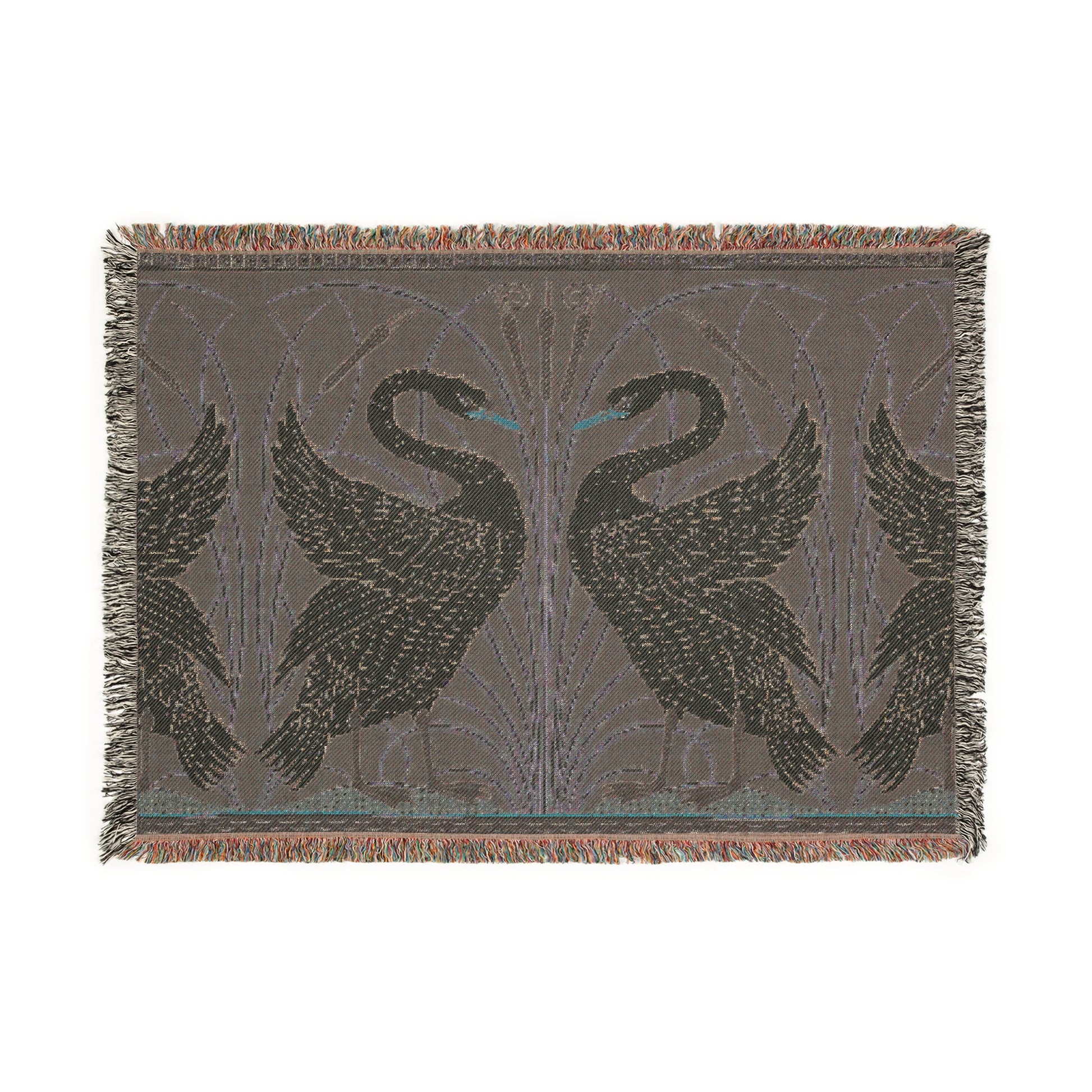 A woven cotton blanket with a geometric William Morris & Co pattern featuring swan motifs in a white and green colour scheme with colourful fringed edges.