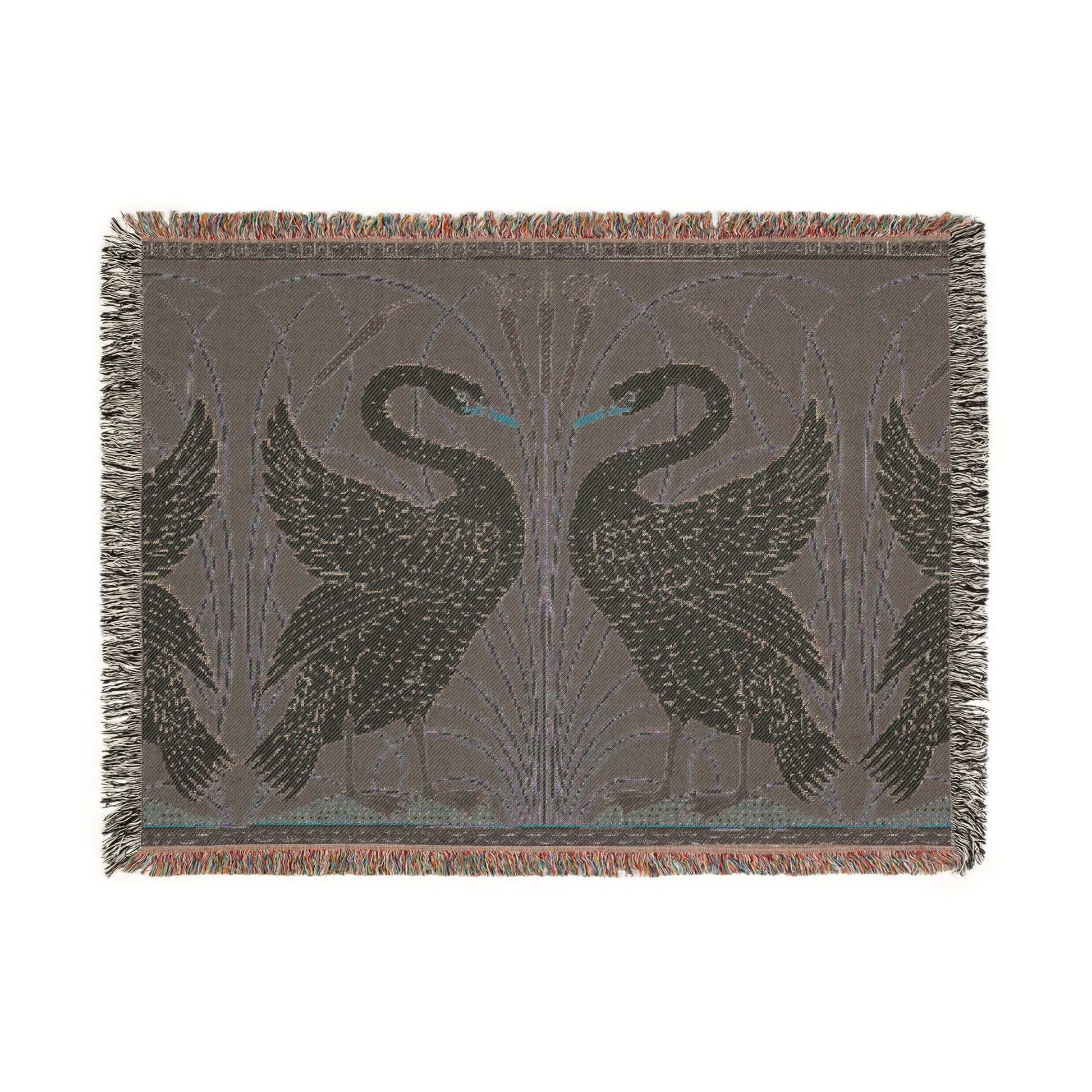 A woven cotton blanket with a geometric William Morris & Co pattern featuring swan motifs in a white and green colour scheme with colourful fringed edges.