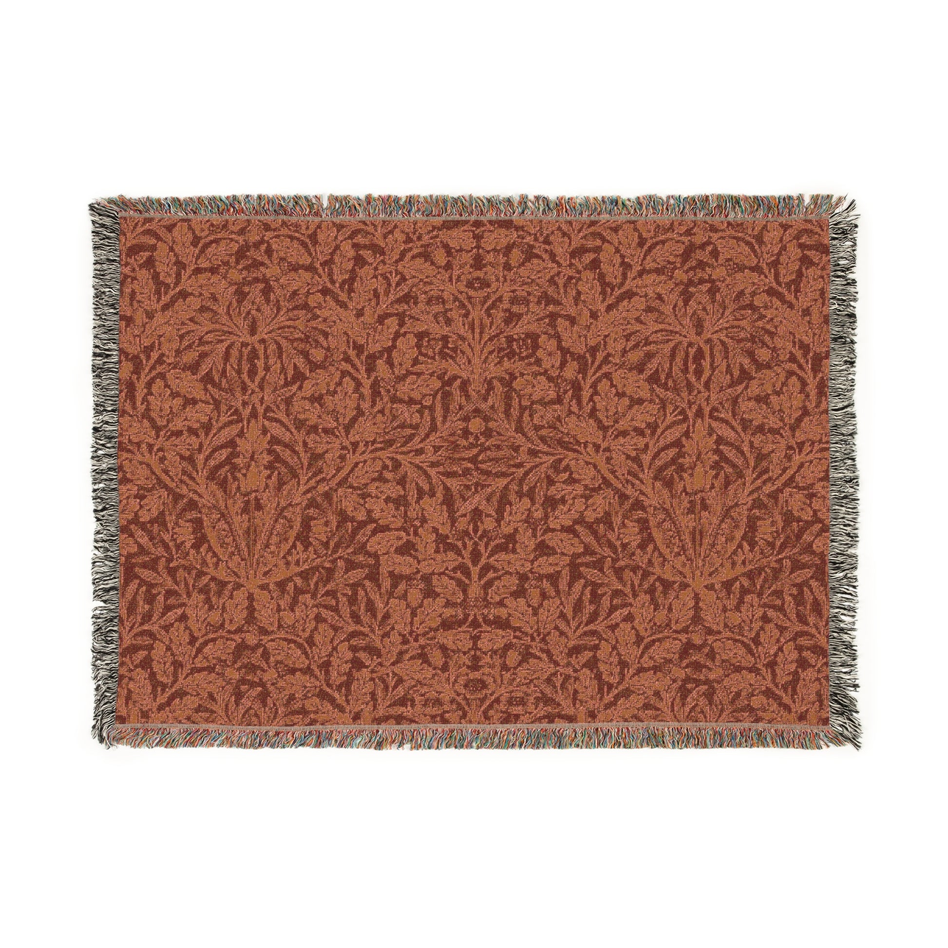 A woven cotton blanket with a floral William Morris & Co geometric pattern in a rust colour, featuring a colourful fringed edge.